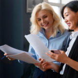 uśmiechnięte kobiety sprawdzające dokumenty